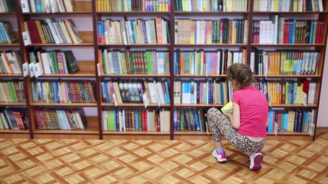 Woman kneeling before book shelves